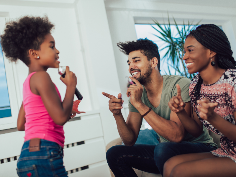 young girl with microphone singing to parents