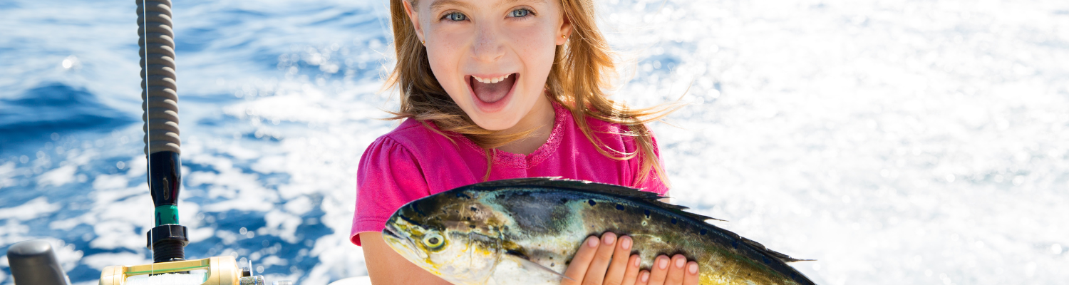 girl in pink shirt on a boat holding fish